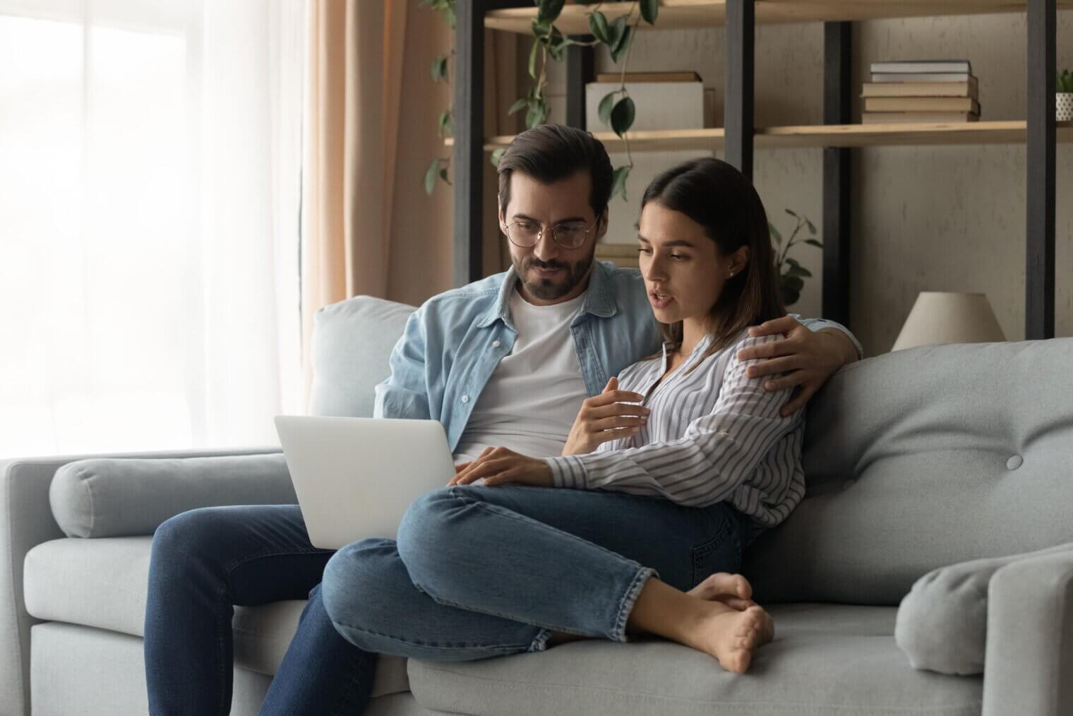 Two people relaxing on a sofa using a laptop to contact the leasing team at Venice Shores.